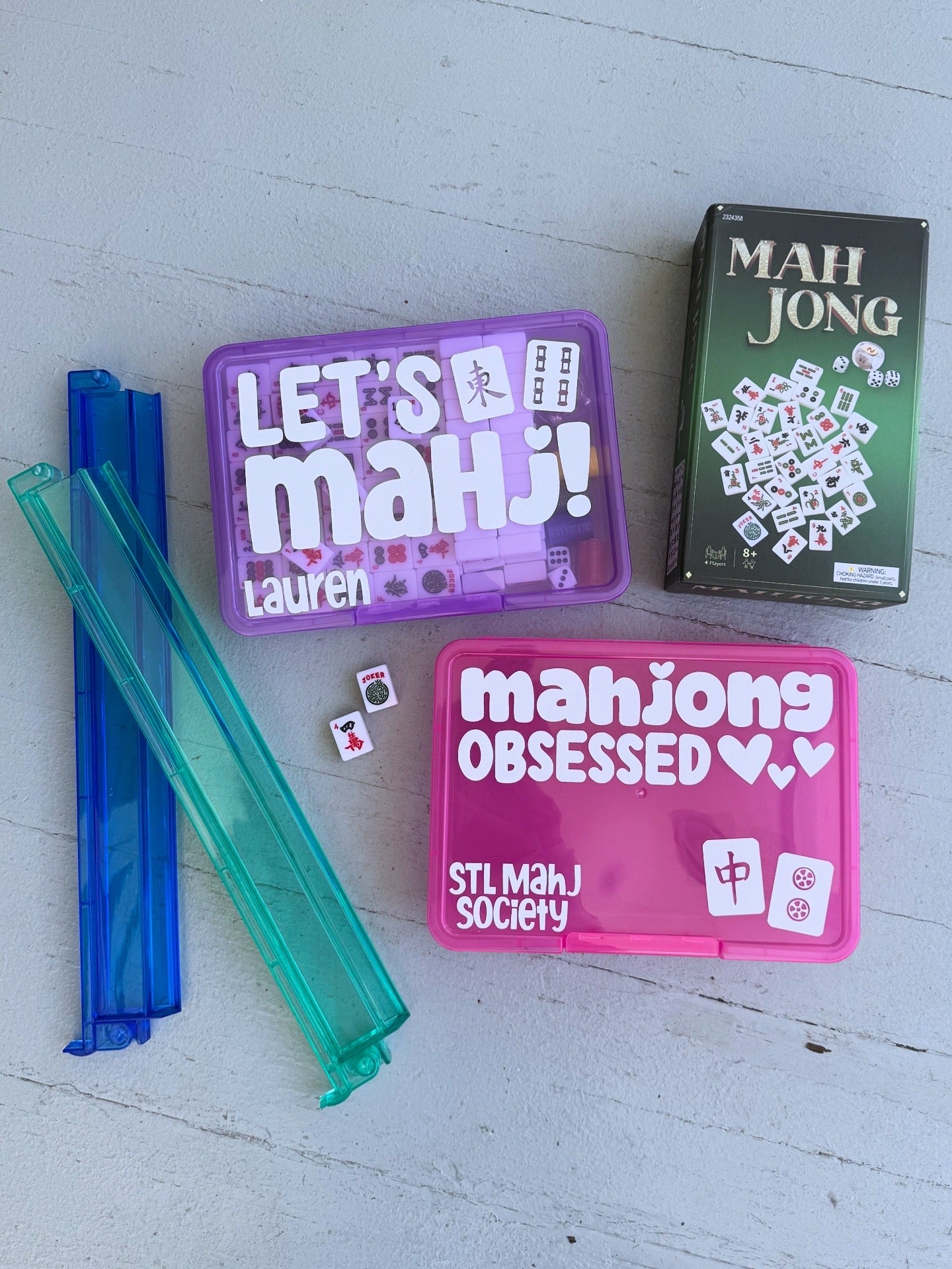 Mahjong game components including tiles, a purple box, and a green box on a light gray surface.