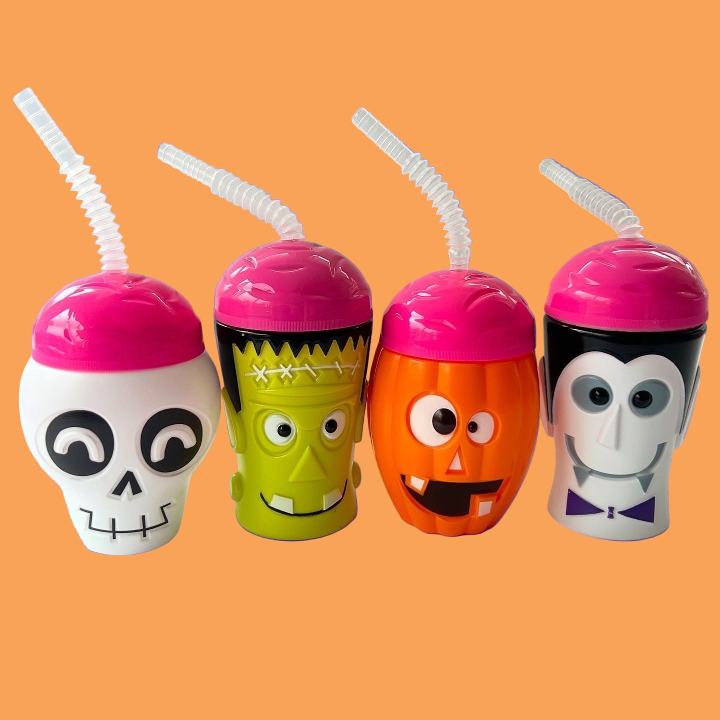 Four Halloween-themed cups with colorful designs and pink lids on a white background