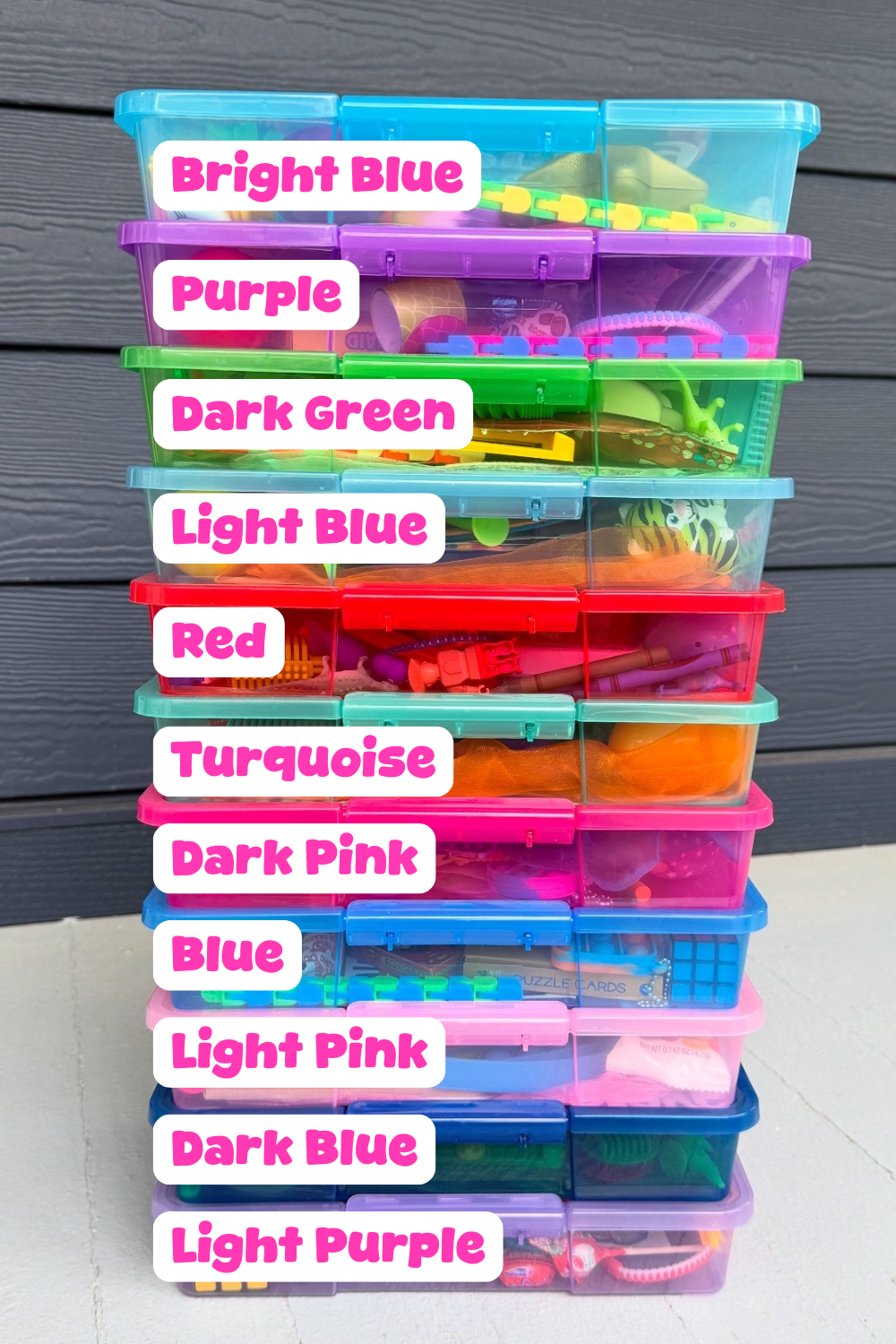 Stack of colorful plastic storage bins with labels on a wooden surface.