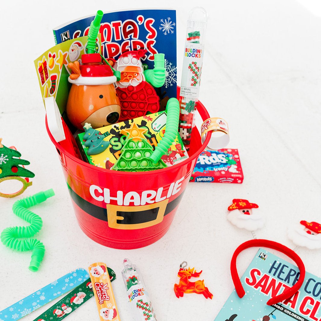 Gift basket labeled 'Charlie' which includes toys, coloring book, fidgets, candy, crayons and more on a white background.