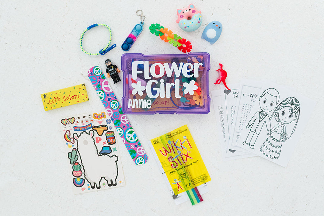 Collection of party favors including a 'Flower Girl' bag, lanyards, and coloring books on a white background.