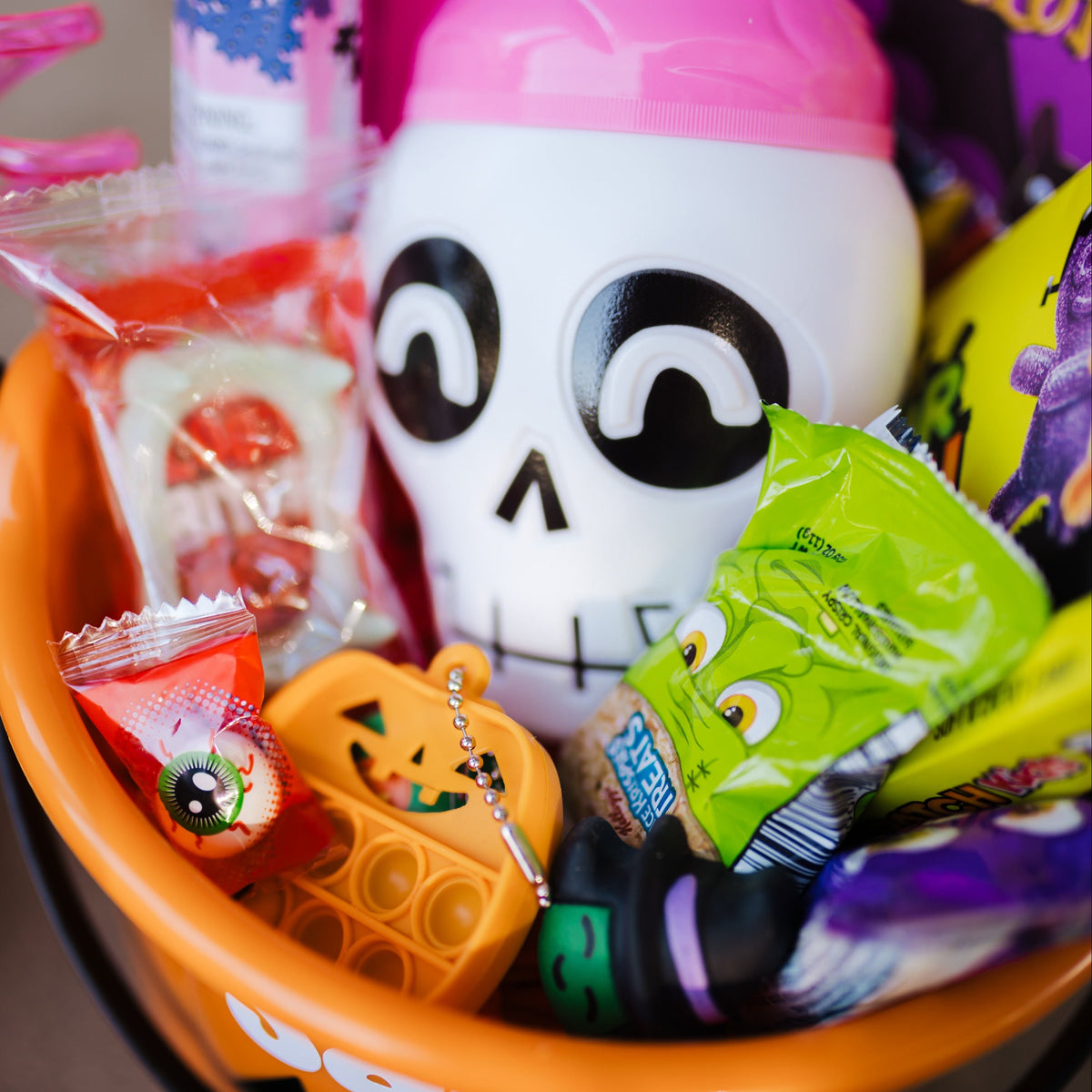 Halloween-themed basket with candy and a skull-shaped toy.