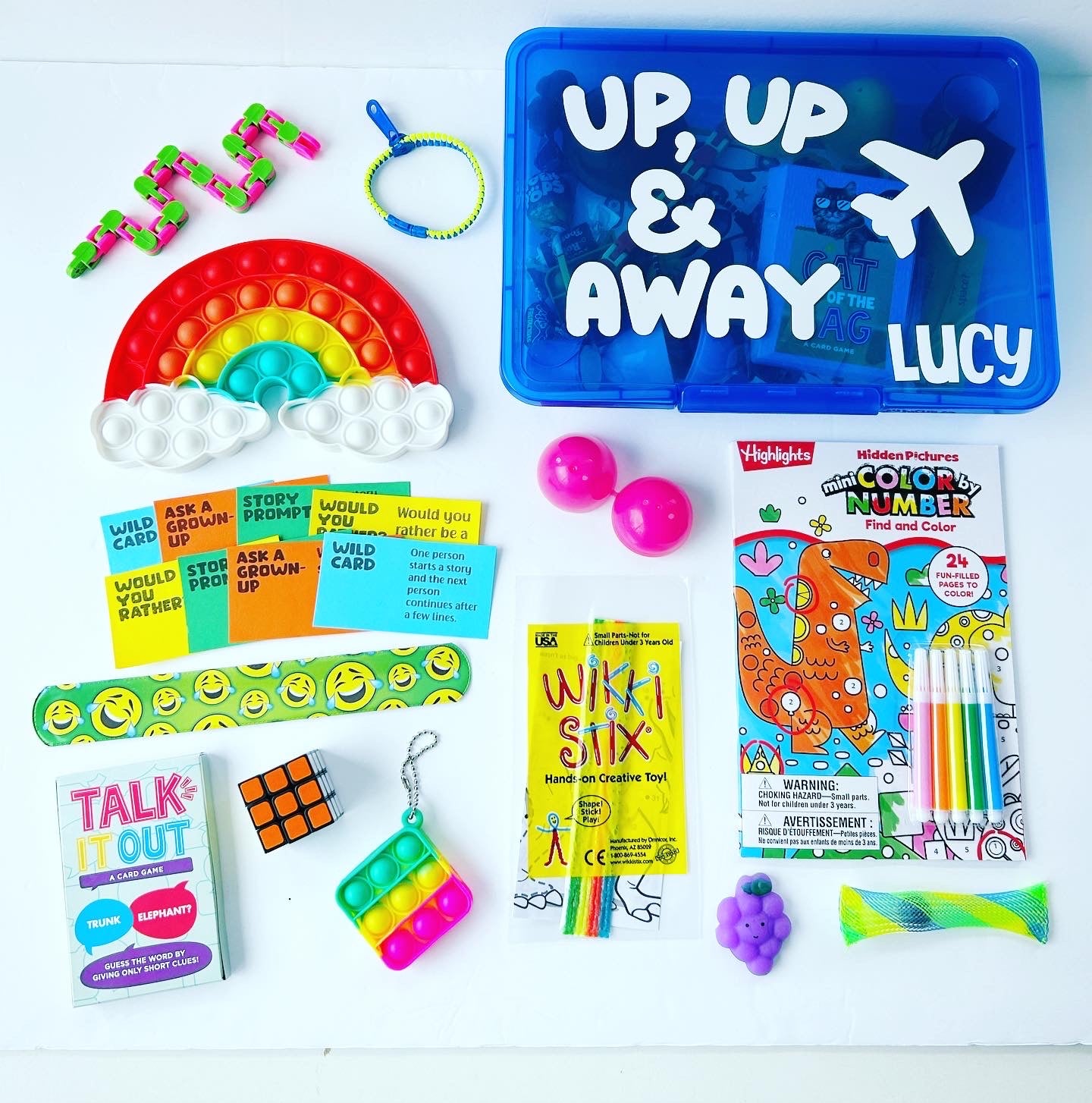 Teen and adult blue busy box with up up and away wording, name Lucy, picture of airplane. Rainbow pop it, dinosaur color by number, fidgets, activity cards, Wikki Stix, talk it out playing cards, Rubiks cube, zipper bracelet, marble mesh, squishy.