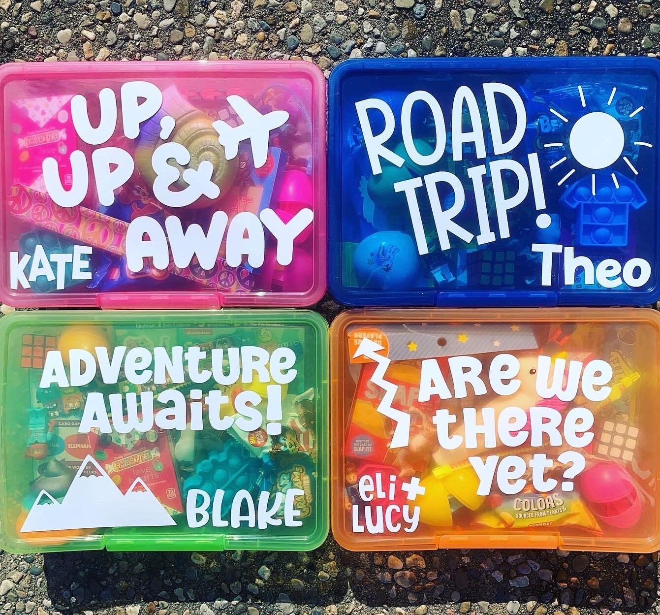 bright colored travel activity boxes - pink box with "up, up and away" with airplane, dark blue box with "road trip" and a sunshine, green box with "adventure awaits" and mountain, orange box with "are we there yet?" and arrow - all personalized with child's name