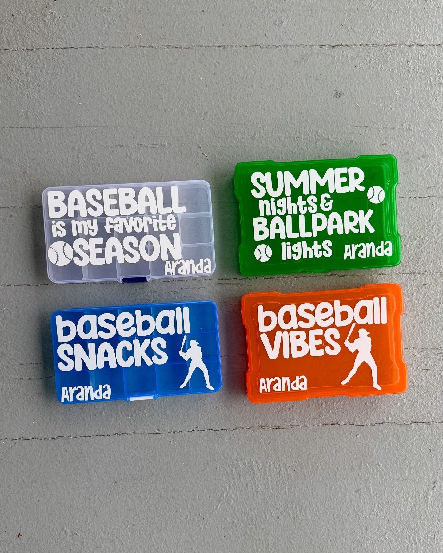 Four colorful rectangular containers with baseball-themed text on a gray surface