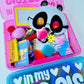 Colorful toy set with panda mask and various items in a pink container on a white background.