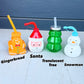 Four festive-themed drinking bottles with straws on a light surface.