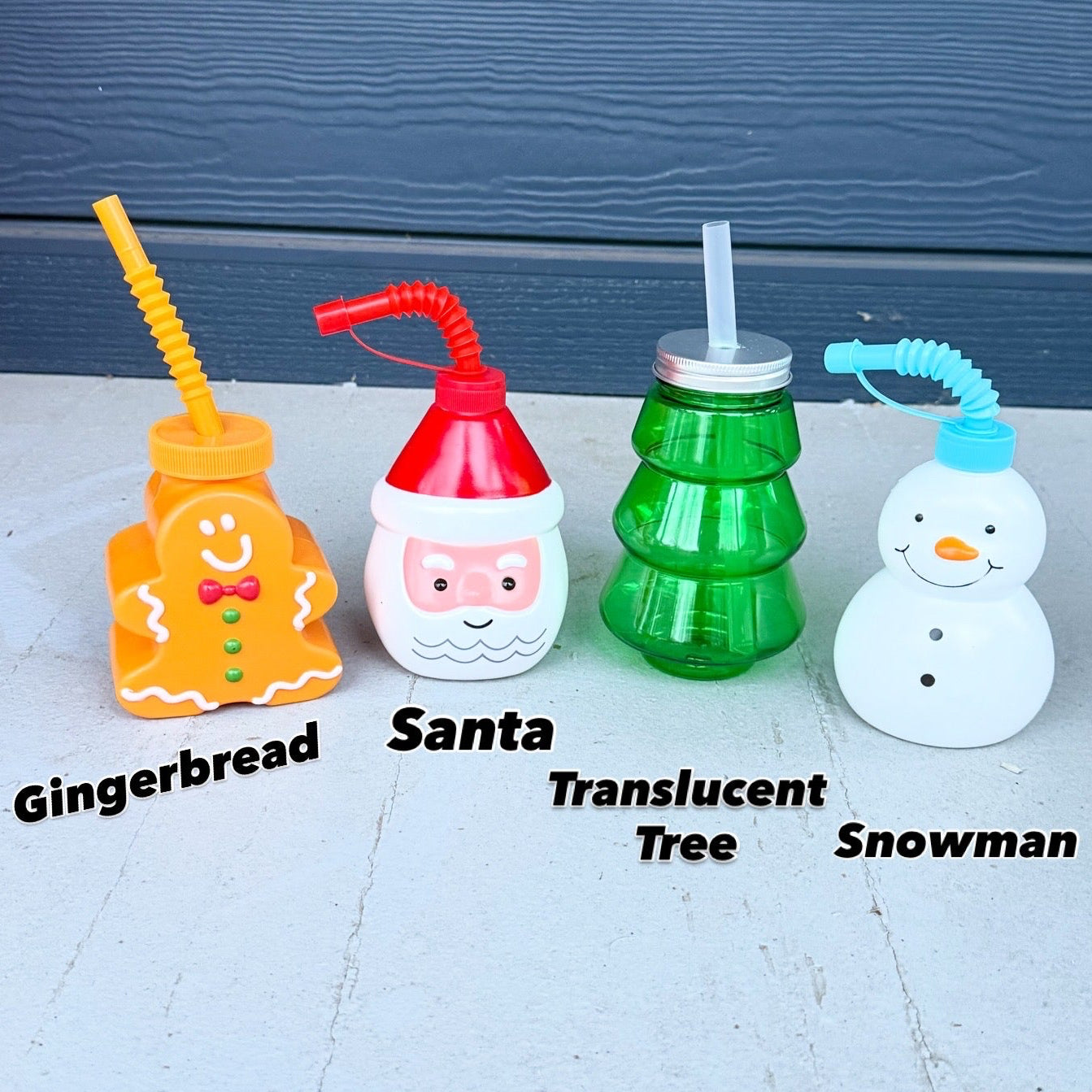 Four festive-themed drinking bottles with straws on a light surface.