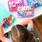 Child playing with a 'Calm Down Kit' while other kits labeled 'Brain Break' and 'My Name is Wiggles' are visible on a table.