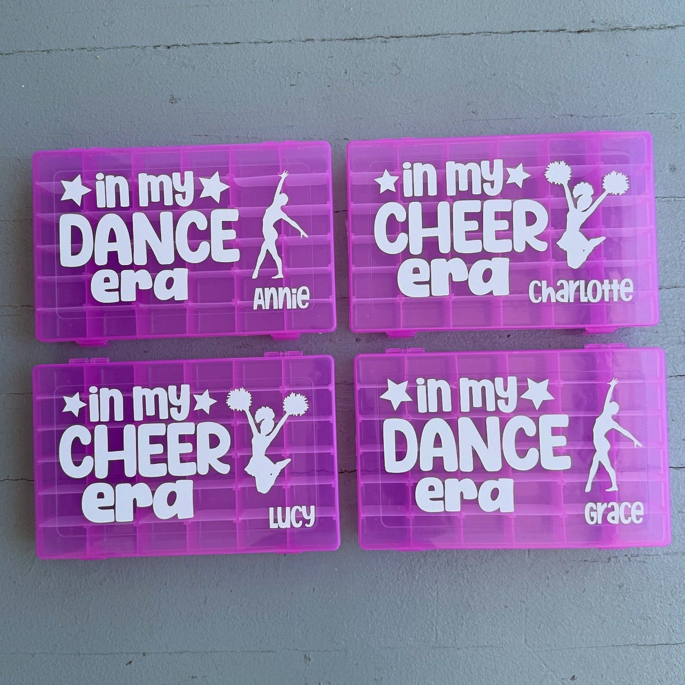 Four pink nameplates with white text and graphics on a gray surface