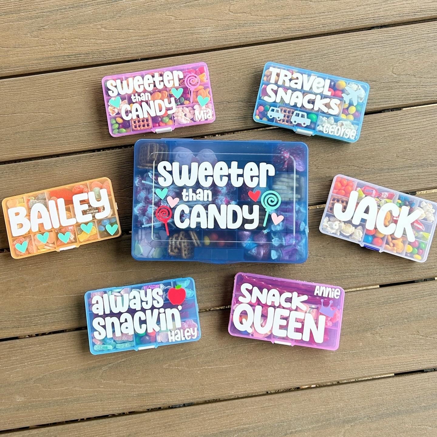 6 travel snack boxes filled with treats. Pink boxes with sweeter than candy and snack queen. Blue boxes with always snackin, travel snacks and sweeter than candy wording. Orange box with name Bailey and hearts. Clear box with name Jack.