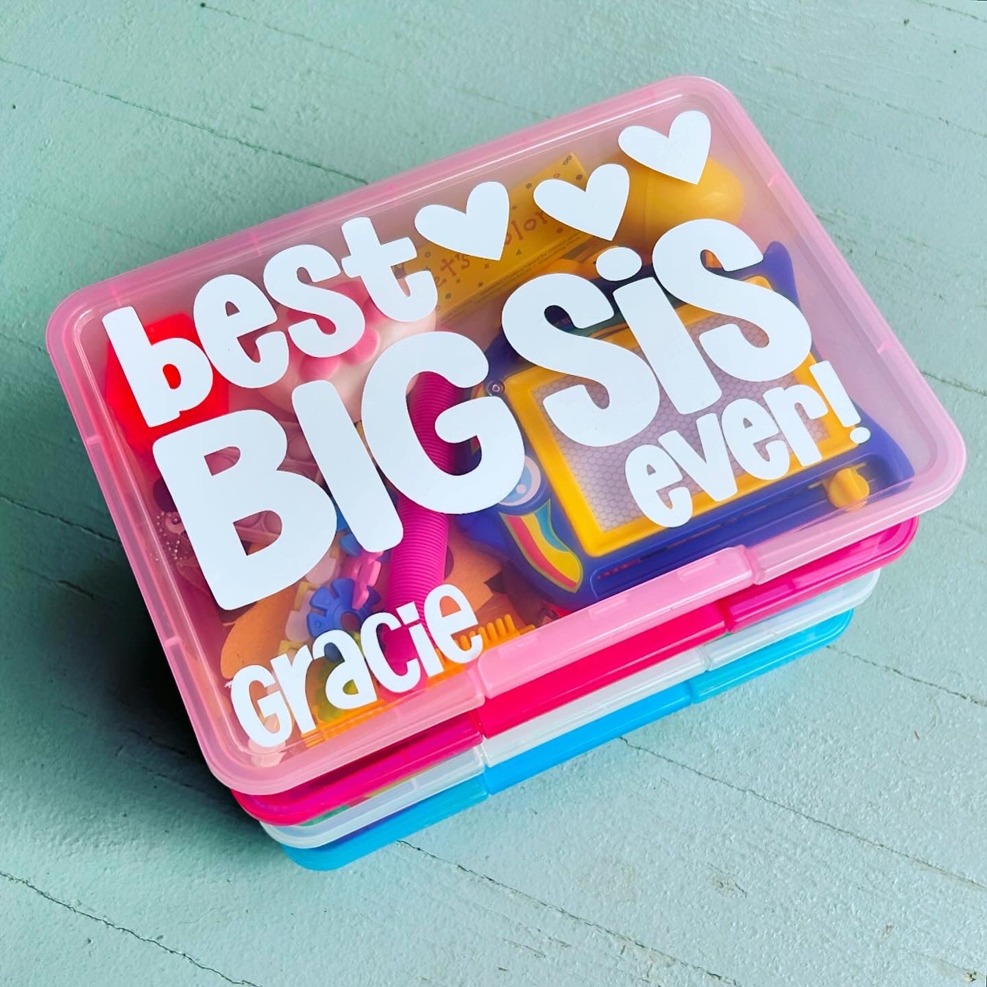 Colorful container with 'best big sis ever' text on a light blue background