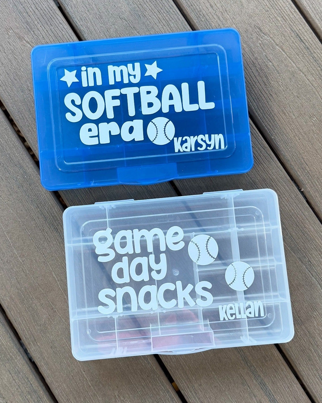 Two plastic containers with 'in my SOFTBALL era' and 'game day snacks' text on a wooden surface.