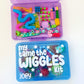 Colorful 'my tame the WIGGLES Kit' with various toys on a white background