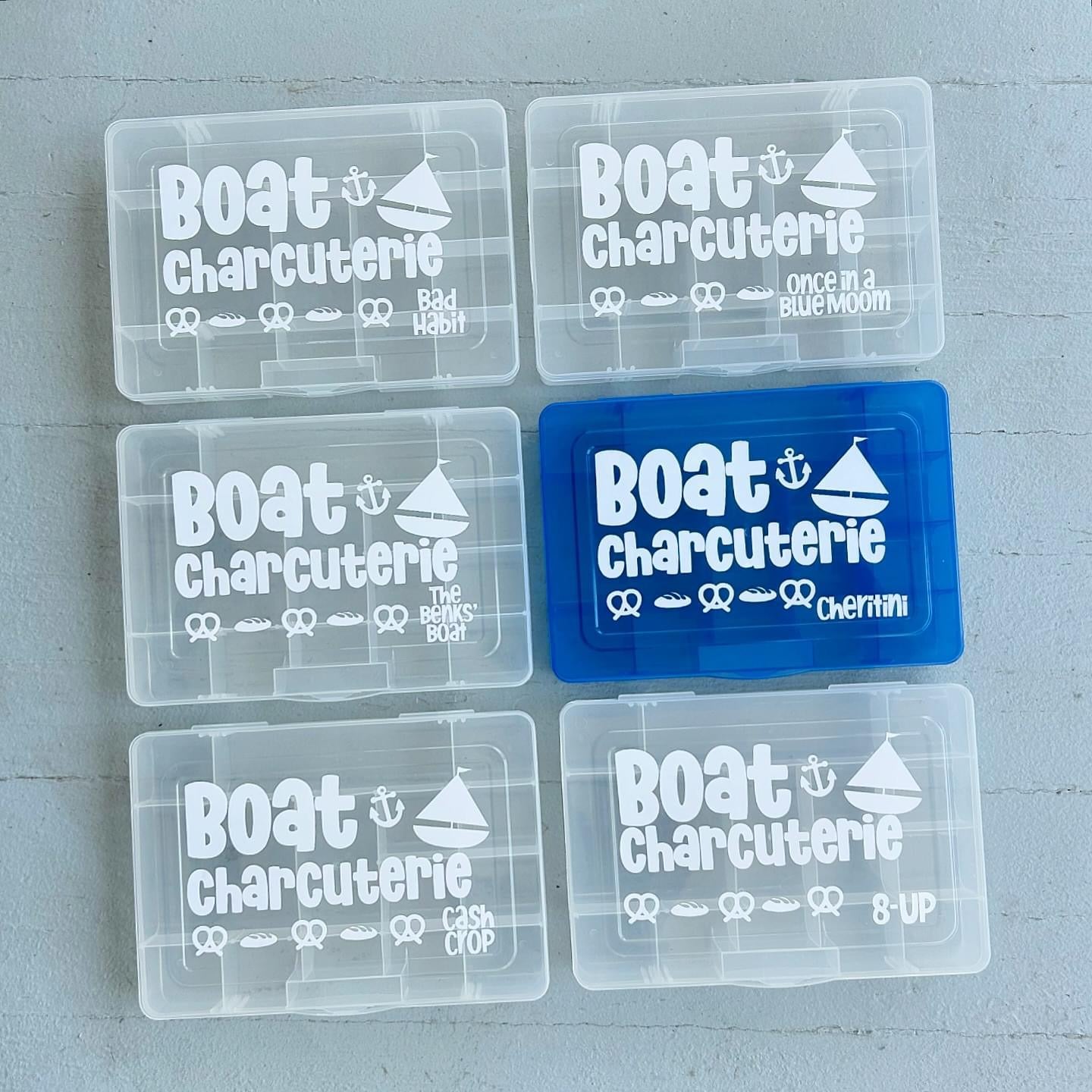 Set of clear plastic containers with 'Boat Charcuterie' branding on a gray surface.