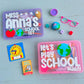 Educational toys and items on a light blue surface with 'Miss Anna's School Set' and 'Let's Play School Maddy' containers.