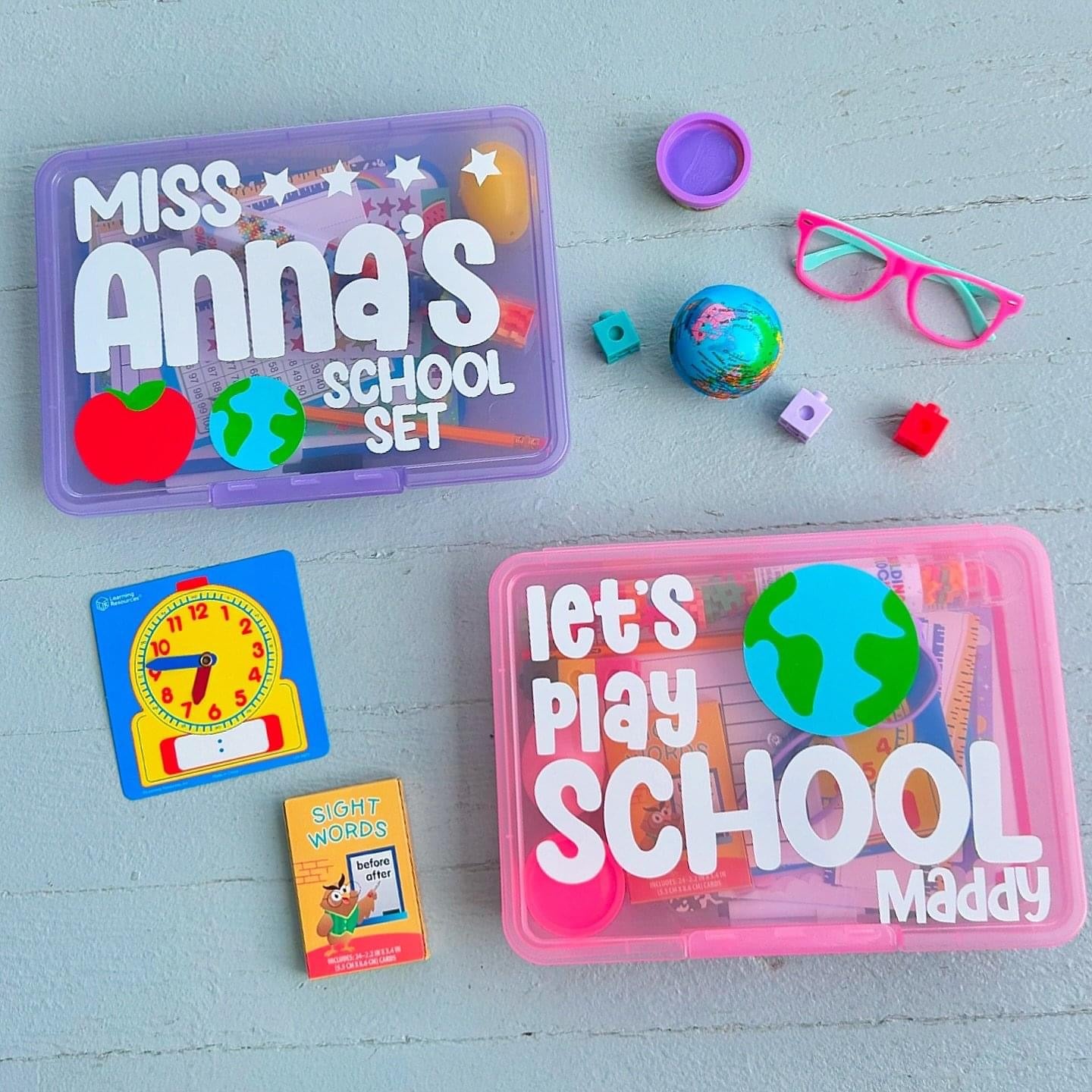 Educational toys and items on a light blue surface with 'Miss Anna's School Set' and 'Let's Play School Maddy' containers.