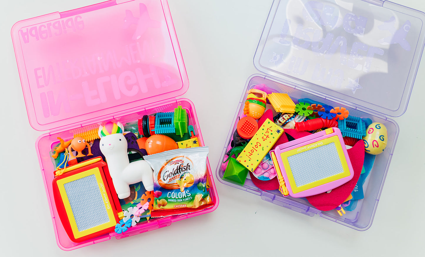 Two plastic toy storage boxes with colorful toys on a white background