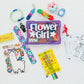 Collection of party favors including a 'Flower Girl' bag, lanyards, and coloring books on a white background.
