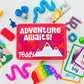 A red toddler travel busy box with the text 'ADVENTURE AWAITS' on the lid, surrounded by various colorful toys and activities including a peekaboo scarf, pop it fidget toy, building blocks, plastic eggs, a slap bracelet, pop tubes, a slow-rise squishy, and learning flashcards.