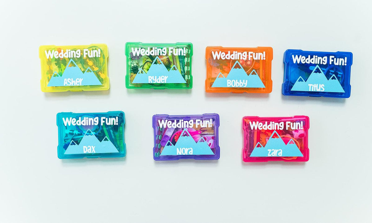 Colorful wedding-themed activity kits with mountain images on a white background. Each wedding favor for kids is personalized and filled with activities to keep kids entertained on your big day.